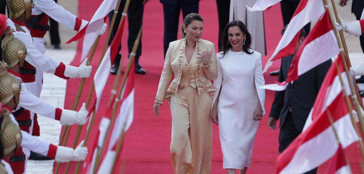 Janja Lula com três peças de seda pura de Helô Rocha, com bordados em palha, pelas bordadeiras de Timbaúba, e Lu Alckmin com vestido off-White, de Glória Coelho, bainha altura midi, mangas em pétalas, efeito de meia-capa.