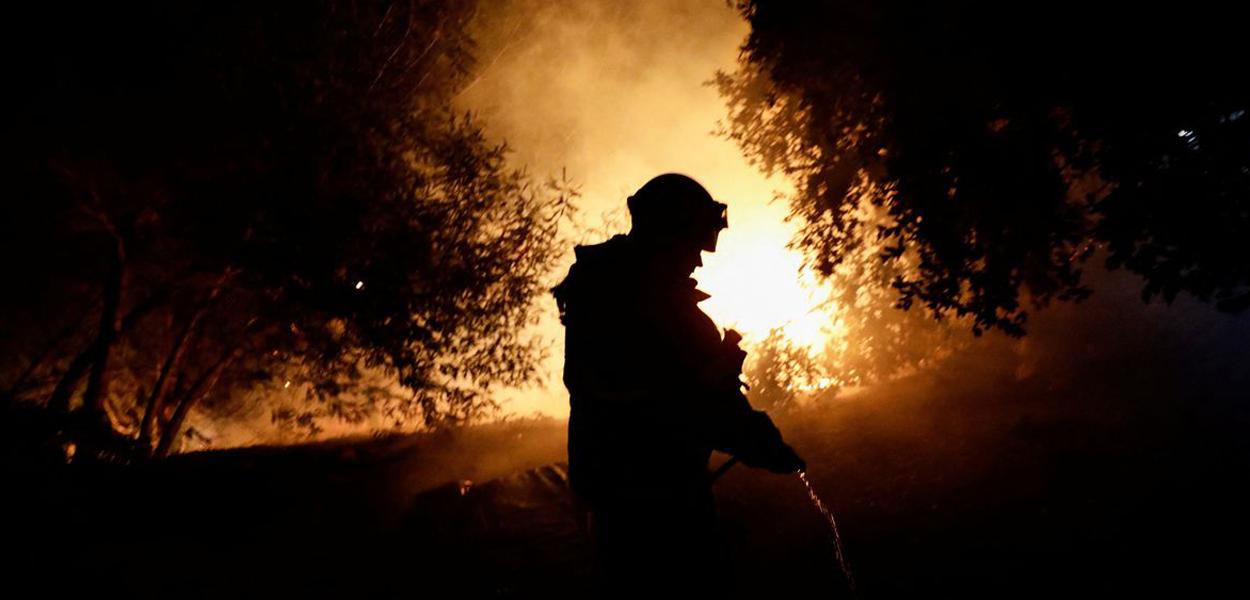 Um bombeiro trabalha enquanto um incêndio florestal queima partes de áreas rurais em Quillon, Chile