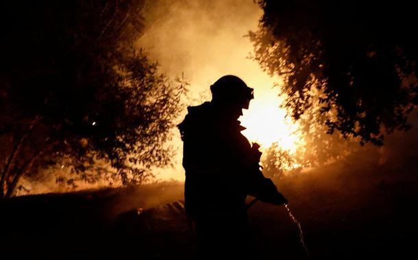 Um bombeiro trabalha enquanto um incêndio florestal queima partes de áreas rurais em Quillon, Chile
