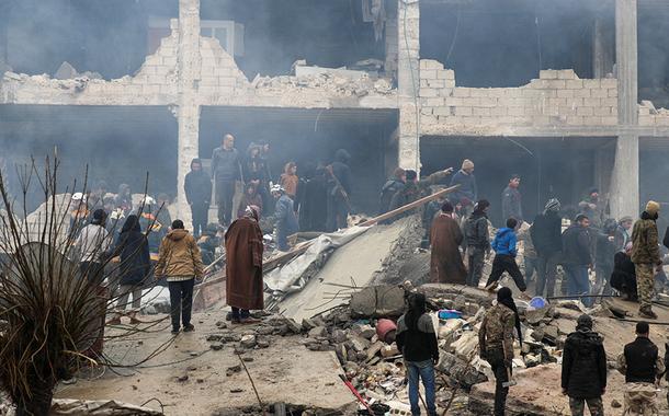 Pessoas e equipes de resgate buscam por pessoas em esombros após terremoto na cidade síria de Jandaris