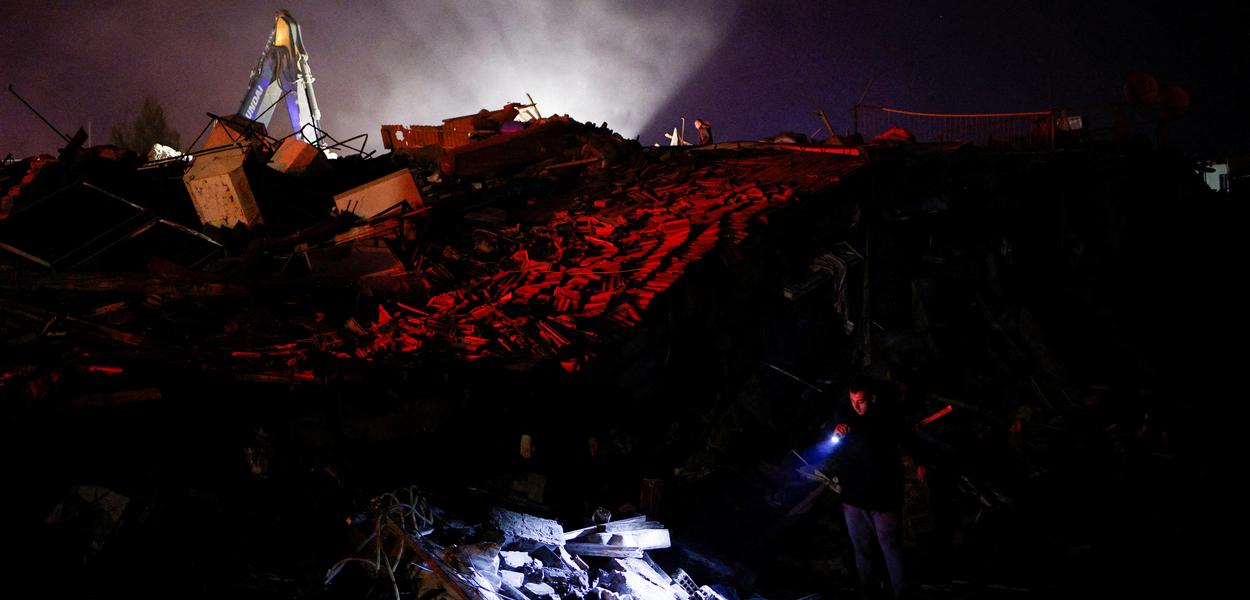 Homem usa lanterna para buscar pessoas após terremoto em Antakya, na Turquia