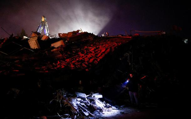 Homem usa lanterna para buscar pessoas após terremoto em Antakya, na Turquia