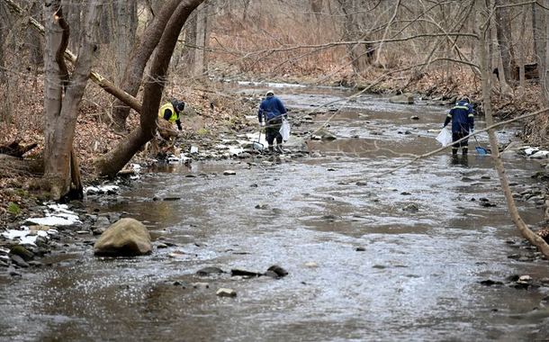 Agentes ambientais removem peixes mortos pela contaminação em um rio próximo ao local de descarrilamento de trem na Palestina Oriental, Ohio, EUA, 6 de fevereiro de 2023