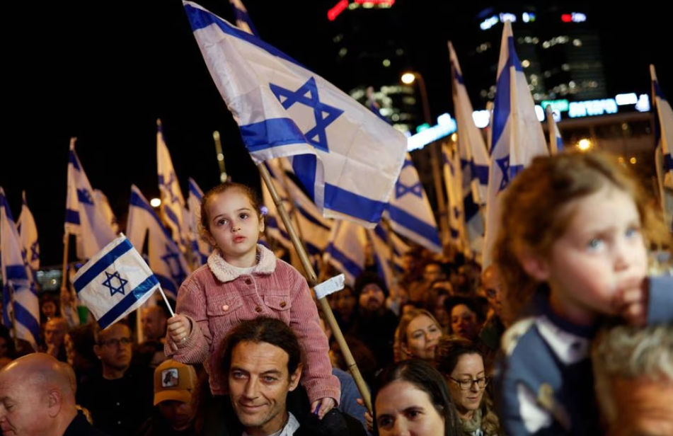 Pessoas seguram bandeiras israelenses durante um protesto contra a nova coalizão de direita do primeiro-ministro de Israel, Benjamin Netanyahu, e suas propostas de mudanças judiciais para reduzir os poderes da Suprema Corte em Tel Aviv, Israel, em 18 de fevereiro de 2023.