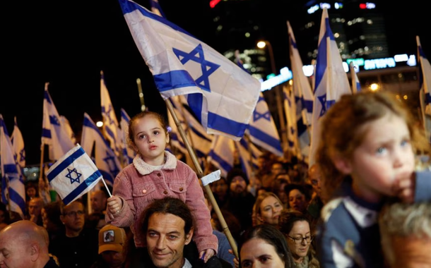 Pessoas seguram bandeiras israelenses durante um protesto contra a nova coalizão de direita do primeiro-ministro de Israel, Benjamin Netanyahu, e suas propostas de mudanças judiciais para reduzir os poderes da Suprema Corte em Tel Aviv, Israel, em 18 de fevereiro de 2023.