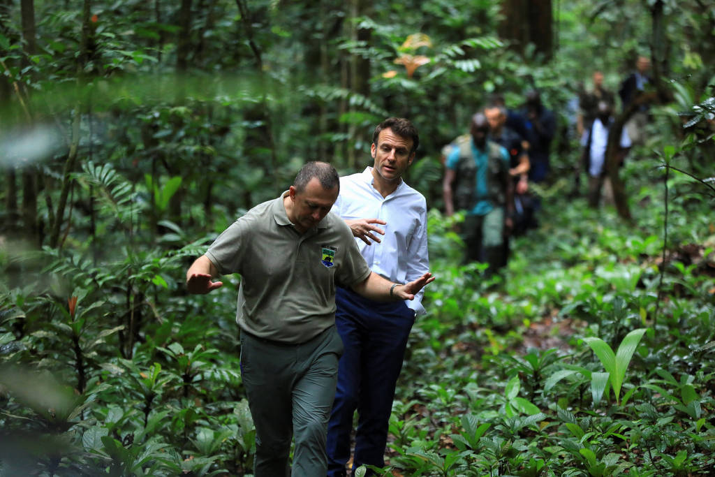 O presidente da França, Emmanuel Macron, caminha ao lado do ministro da Água e das Florestas do Gabão, Lee White, durante visita a área florestal da capital Libreville