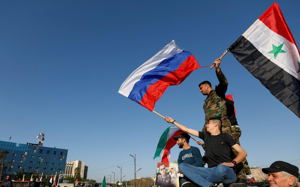 Sírios agitam bandeiras russas e sírias durante protesto contra ataques aéreos liderados pelos EUA em Damasco, Síria, 14 de abril de 2018