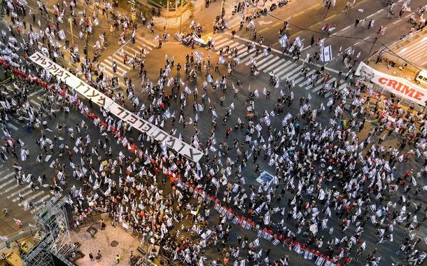 Pessoas vestindo vermelho fazem fila durante uma manifestação contra o primeiro-ministro israelense Benjamin Netanyahu e a reforma judicial de seu governo de coalizão nacionalista, em Tel Aviv, Israel, 8 de abril de 2023.