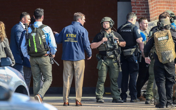 O governador de Kentucky, Andy Beshear, fala com a polícia destacada no local de um tiroteio em massa perto do estádio de beisebol Slugger Field, no centro de Louisville, Kentucky, EUA, 10 de abril de 2023