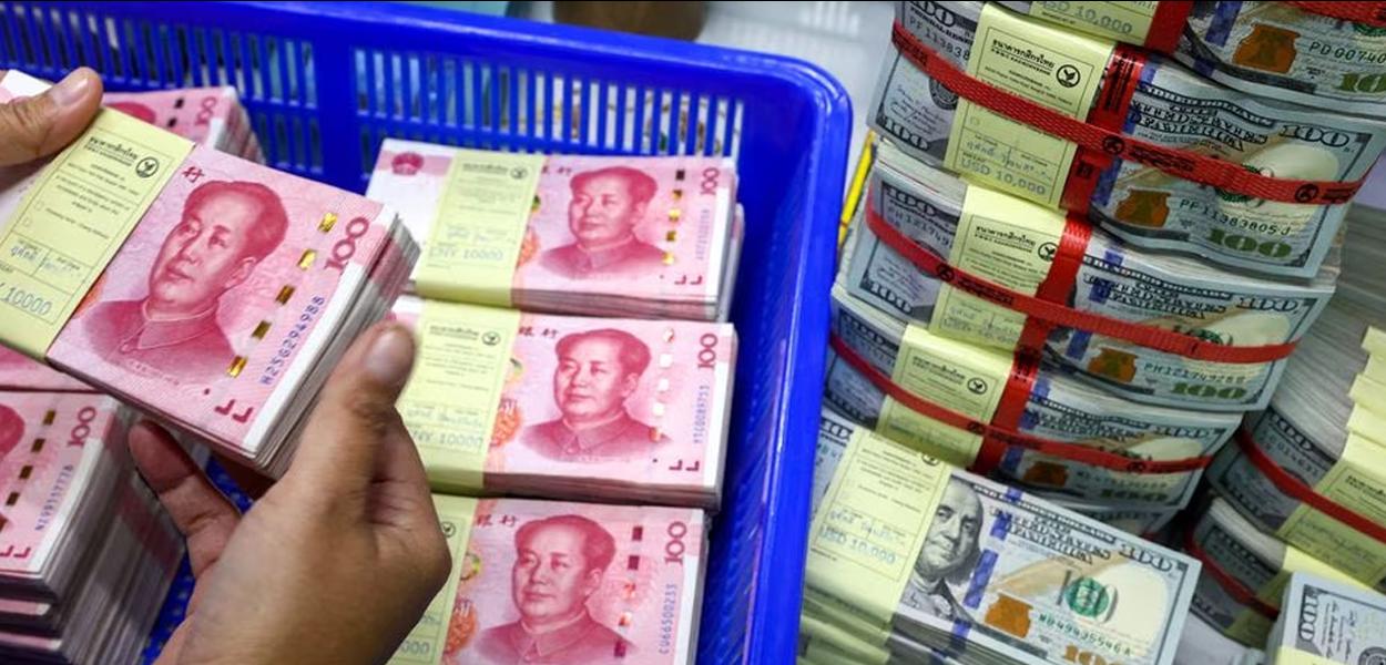 Funcionário de banco conta renminbi da China (RMB) ou notas de yuan ao lado de notas de dólar americano em um Kasikornbank em Bangkok, Tailândia - 26.01.2023