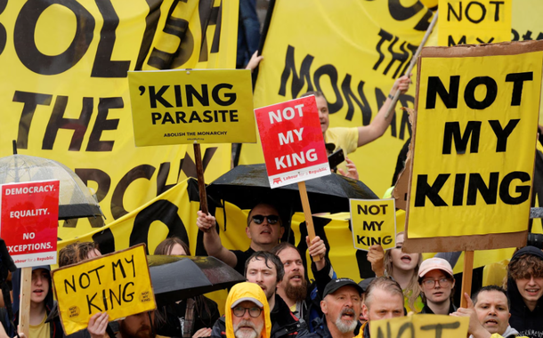 Manifestantes seguram cartazes enquanto as pessoas se reúnem no dia da cerimônia de coroação do rei Charles e da rainha Camilla, em Londres, Grã-Bretanha, 6 de maio de 2023