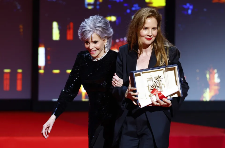 A diretora Justine Triet, vencedora da Palme d'Or pelo filme "Anatomie d'une chute" segura seu prêmio ao lado da atriz Jane Fonda no palco durante a cerimônia de encerramento do 76º Festival de Cinema de Cannes