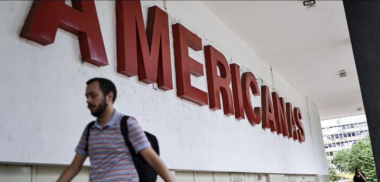 Homem caminha em frente a uma loja Americanas