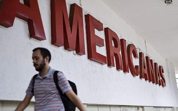 Homem caminha em frente a uma loja Americanas